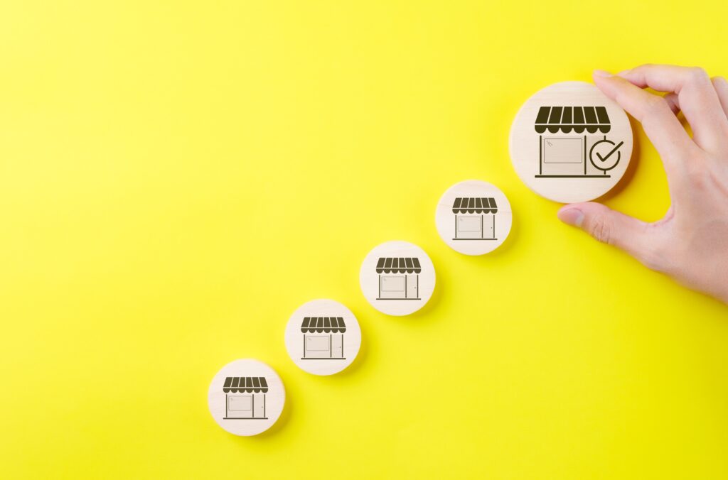 A hand holding miniature buildings, representing market expansion.