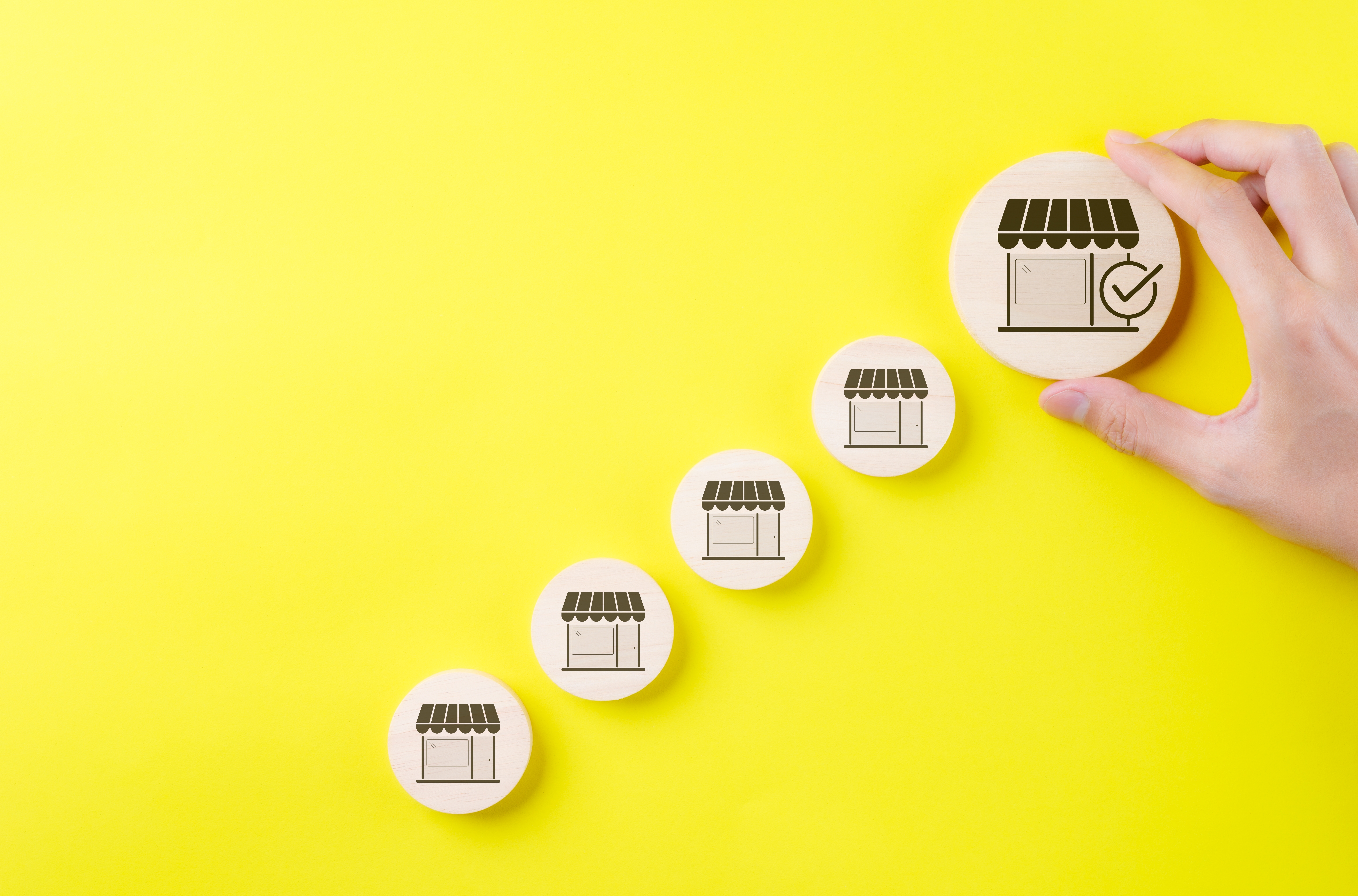 A hand holding miniature buildings, representing market expansion.