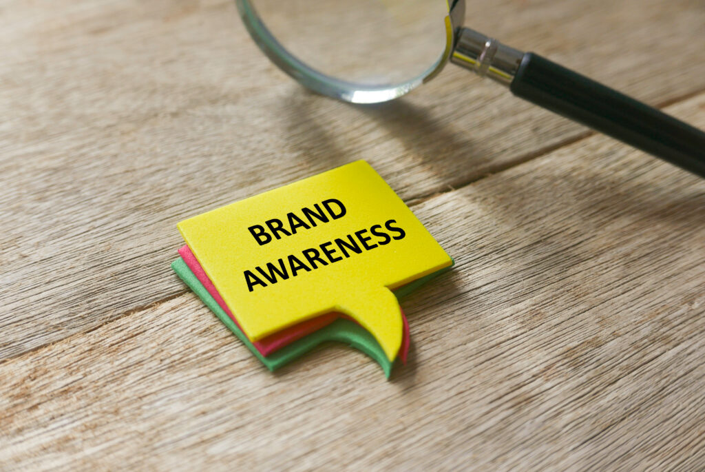 "Brand Awareness" written on a notepad with a magnifying glass beside it.